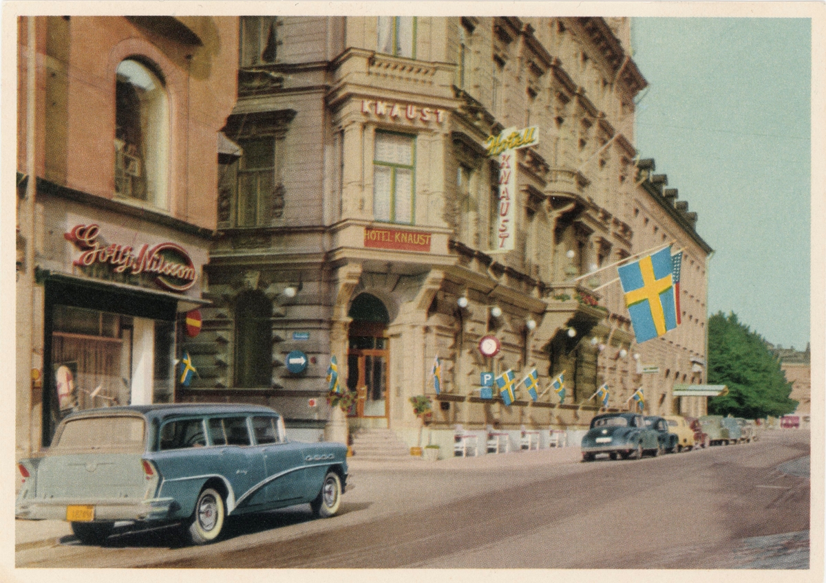 Storgatan. Från vänster Gottfrid Nilssons skoaffär. Mitt i bild Hotell Knaust prytt med en svensk och en amerikansk flagga. Rasterat vykort. Förlag: Norrlandstryckeriet AB, Sundsvall.