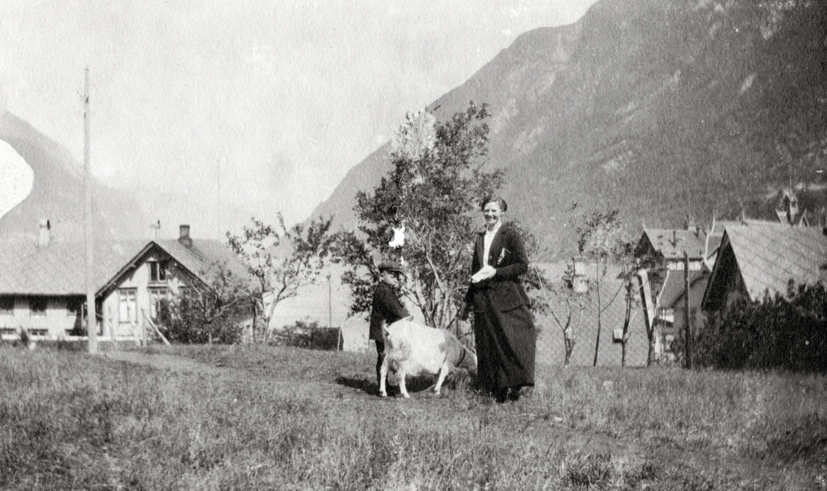 Kvinne og gut med ei geit bak Gamle Hardanger Hotell.