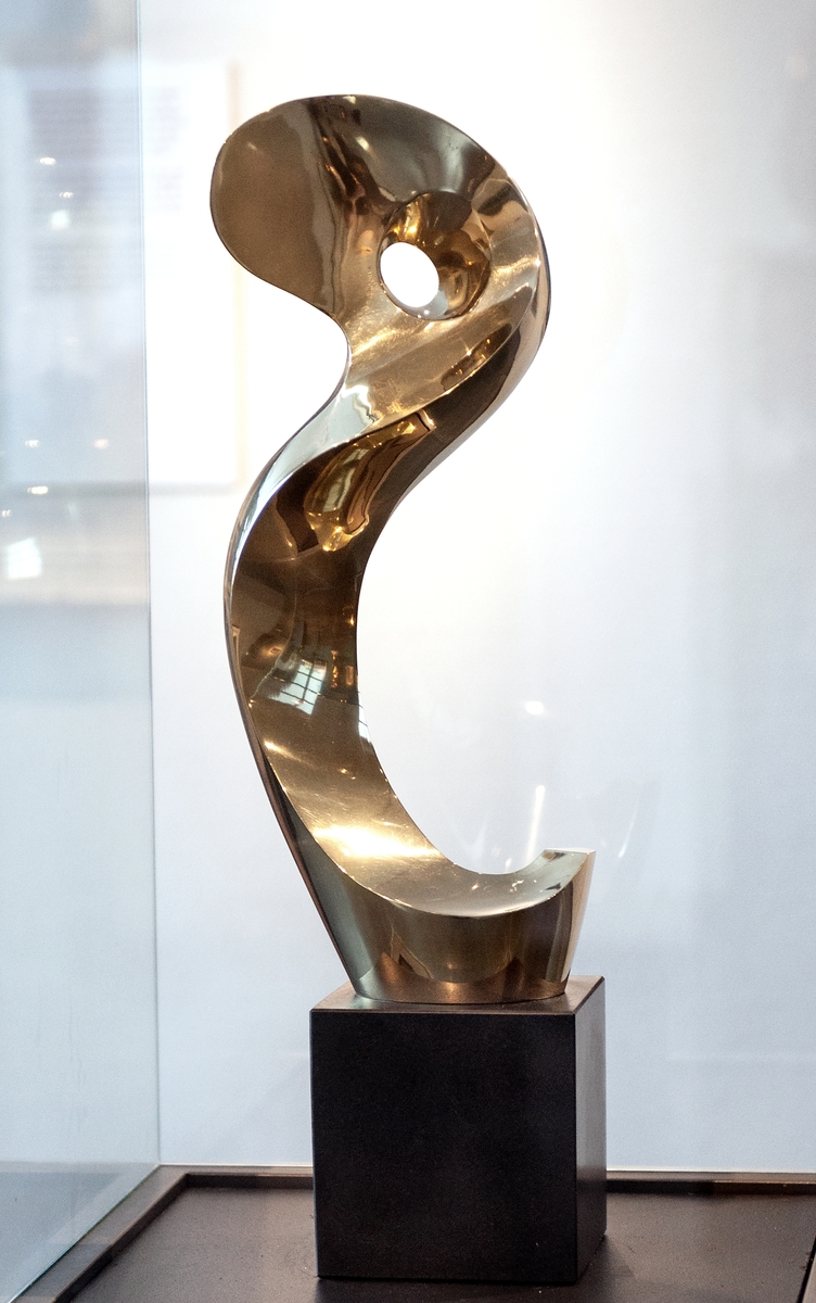 Skulptur av gulpolerad brons, "Snäckan" av Christian Berg. Skulpturen bildar en uppgående spiral som upptill har ett hål. Sockel av svart sten, belgisk marmor.
