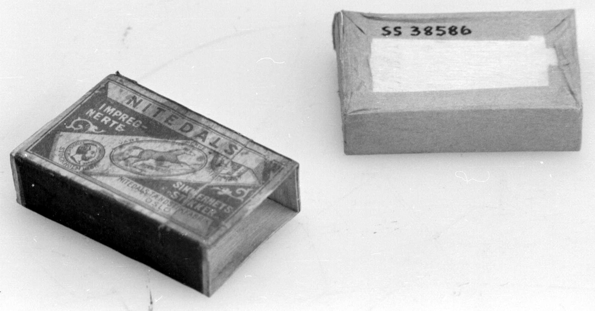 Fyrstikkeske bestående av to deler, en eske som er trukket med rosa papir og kan skyves inn i en annen. På oversiden vises produsentnavnet på et diagonalt bånd med en hest og to mannshoder. På begge sider er det ripeflater. Reklame på baksiden.