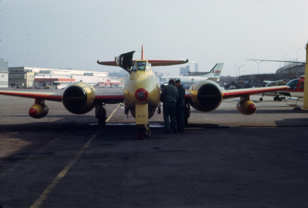 Gulmålat målbogserflygplan av typ Gloster Meteor T.7 med civilt registreringsnummer SE-CAS på Bromma flygplats, i början av 1970-talet. Flygförare och flygtekniker i arbete. Serie om 7 bilder.