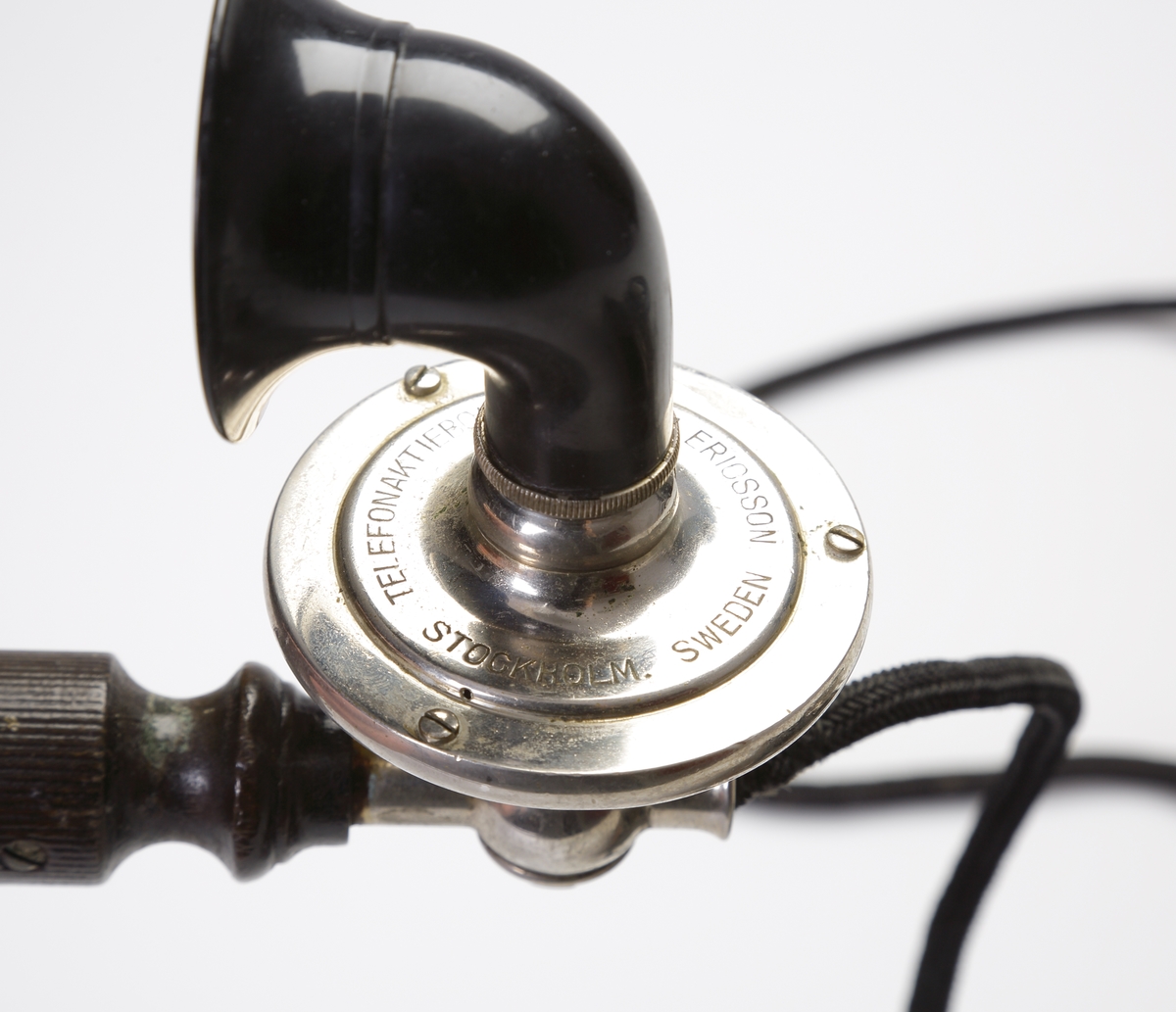 Telefon, bordsmodell. 
Rektangulär, svart bakelitmodell med detaljer av nickel. Telefonlur med svart tygsladd.