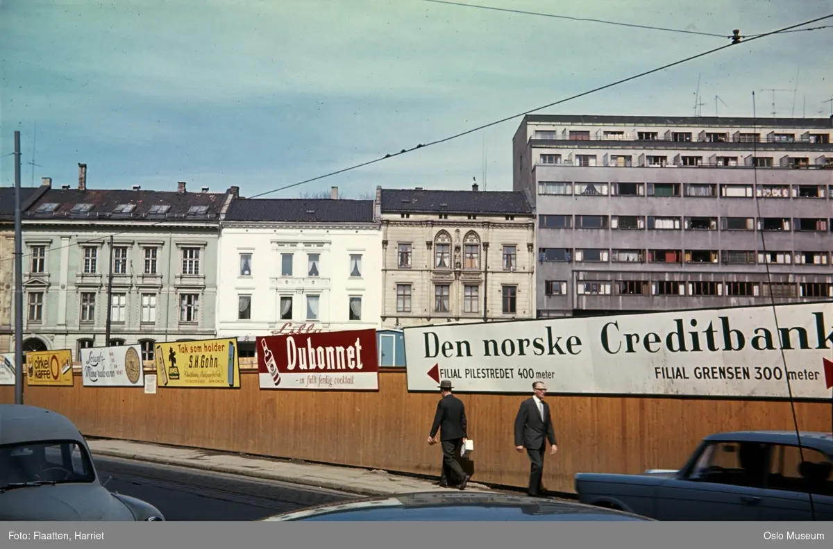 byggetomt for Oslo Helseråds kontorbygning, plankegjerde, reklameplakater, biler, menn, bygårder