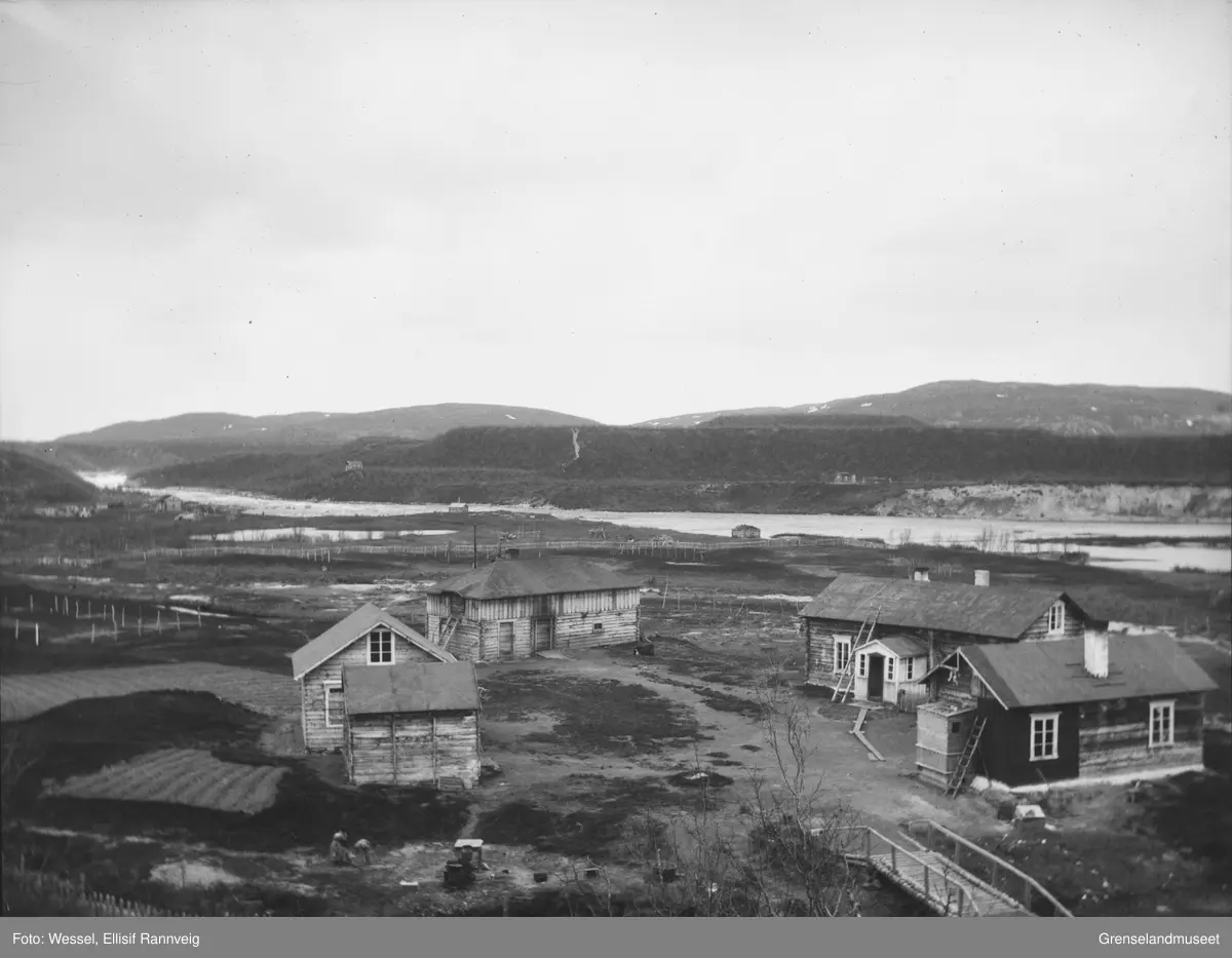 Handelsmann A. Wartiainens gård i Neiden, 1905. I bakgrunnen ses St. Georgs kapell og skoltebyen med skoltesamenes boplass ved fossen.