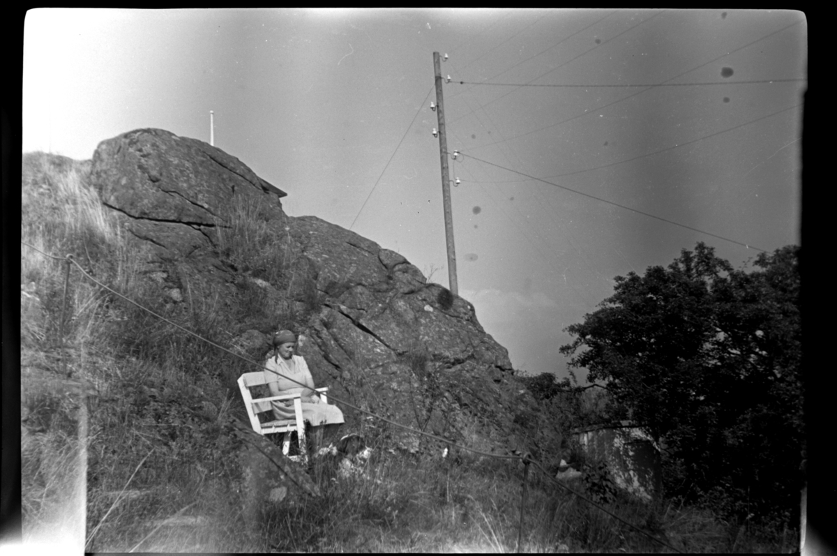 Agnes Sundt sitter på en benk bak huset sitt i Loshavn. Fotografert ca. 1953.