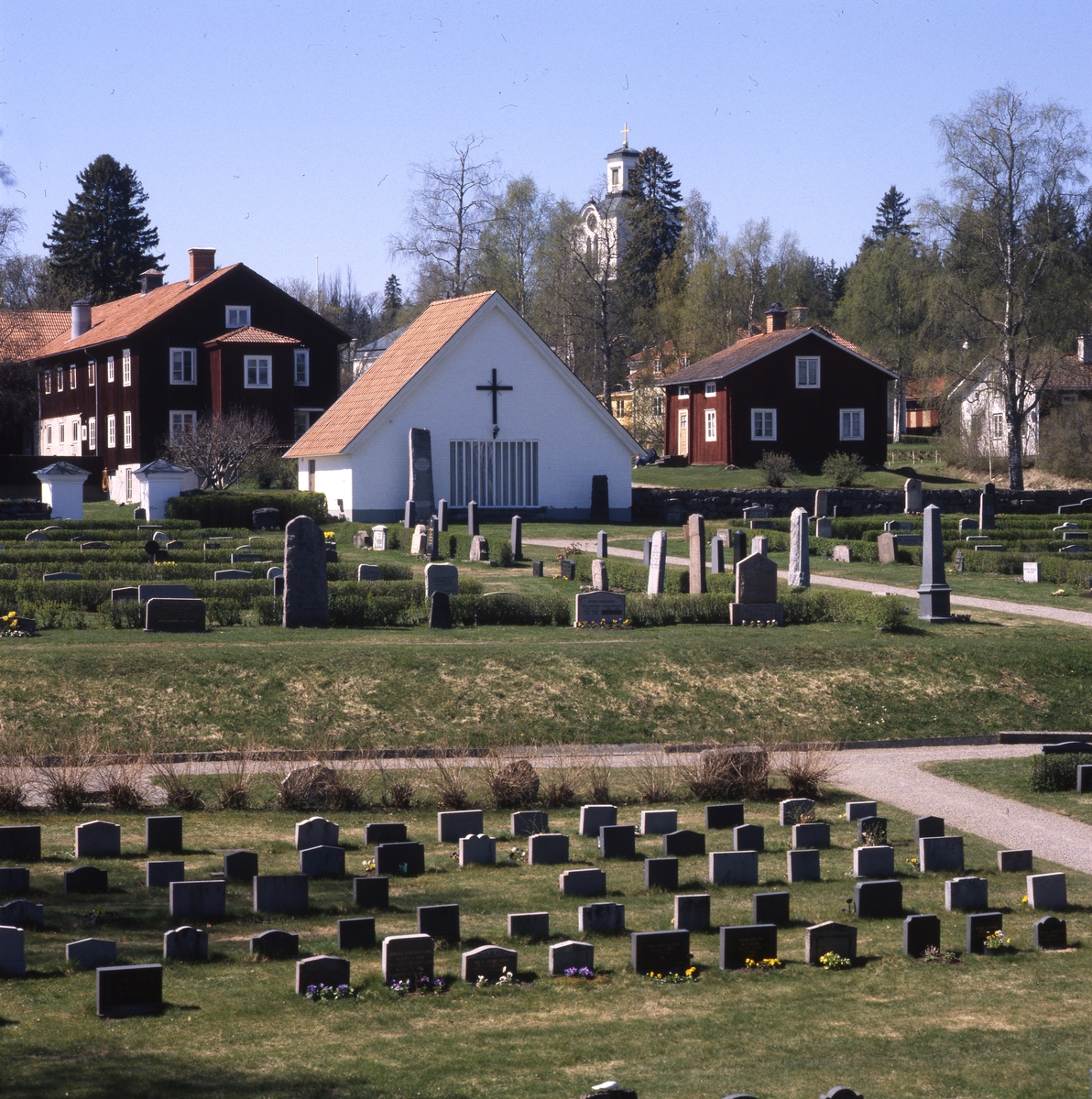 "Lannbonns" det vill säga kyrkans landboställe, sett från nedre kyrkogårdsdelen. Rengsjö kyrka i bakgrunden, 20 och 22 maj 1999.