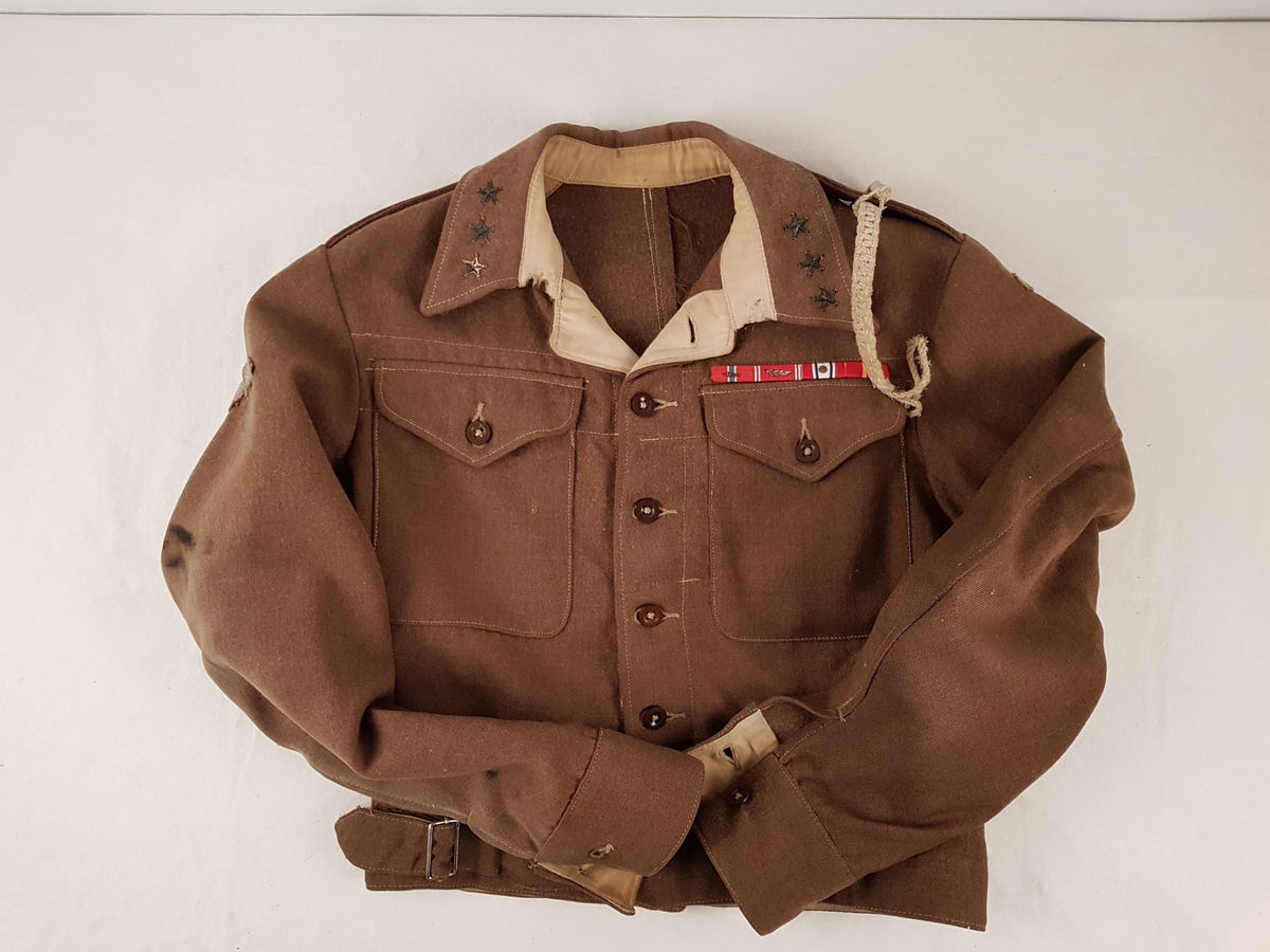 Uniformen består av jakke, bukse, beret, skjorte, slips, armbind, belte, gamasjer og støvler.