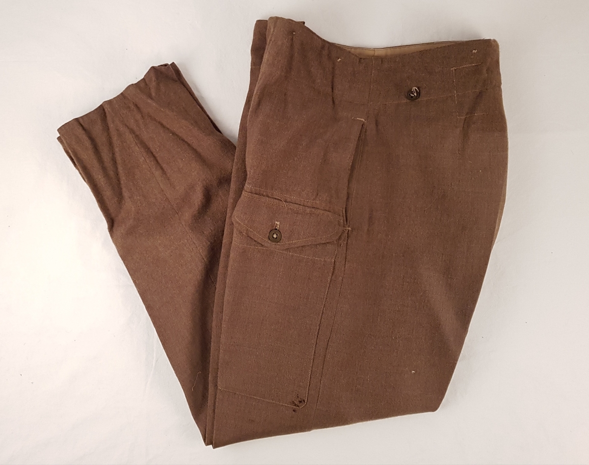 Uniformen består av jakke, bukse, beret, skjorte, slips, armbind, belte, gamasjer og støvler.