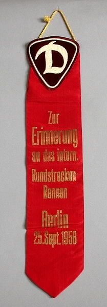Röd vimpel av konstsiden med guldtext: "Zur Erinnerung an das intern. Rundstrecken-Rennen Berlin 25. Sept. 1956".