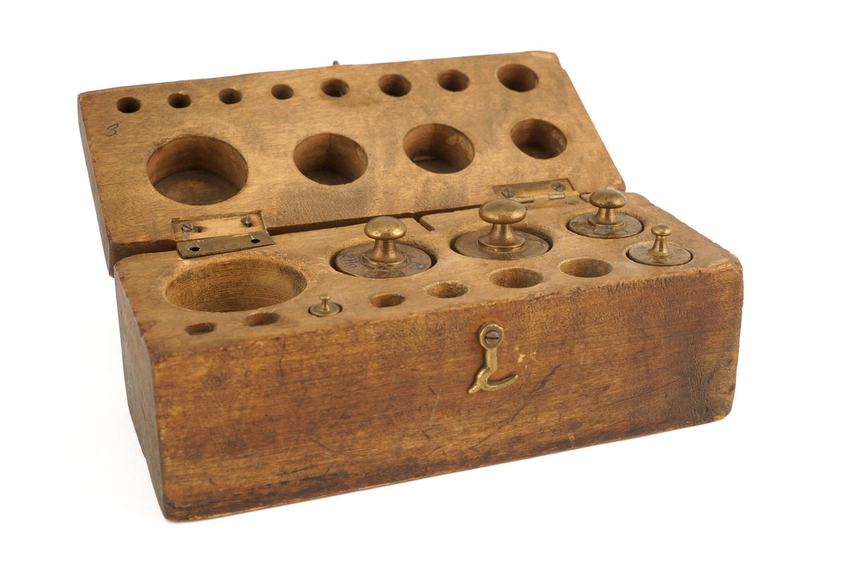 Trekasset inneholdende 5 stk. lodd. Angitt i hg og g.
Det ene hengslet på kassetten er defekt.