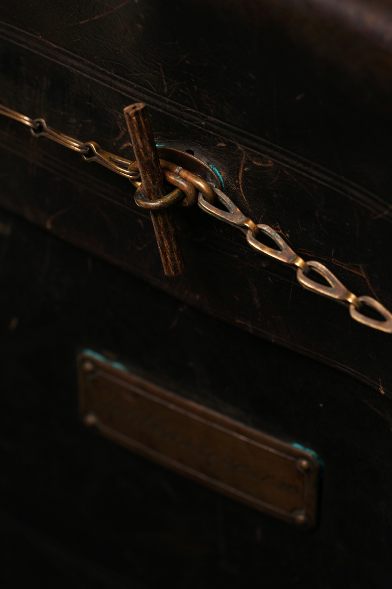 Veske av lær med 9 messingbøyler og to messinglenker for låseanordning. Låsepinne av tre. (Denne ligger i vesken)