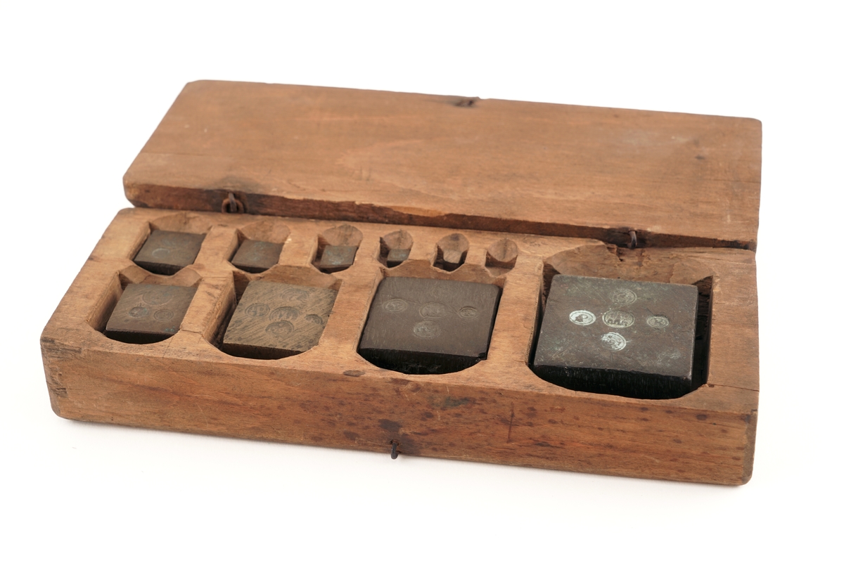 Loddkasse  med lokk av tre, og med 9  lodd av messing. Det minste mangler.