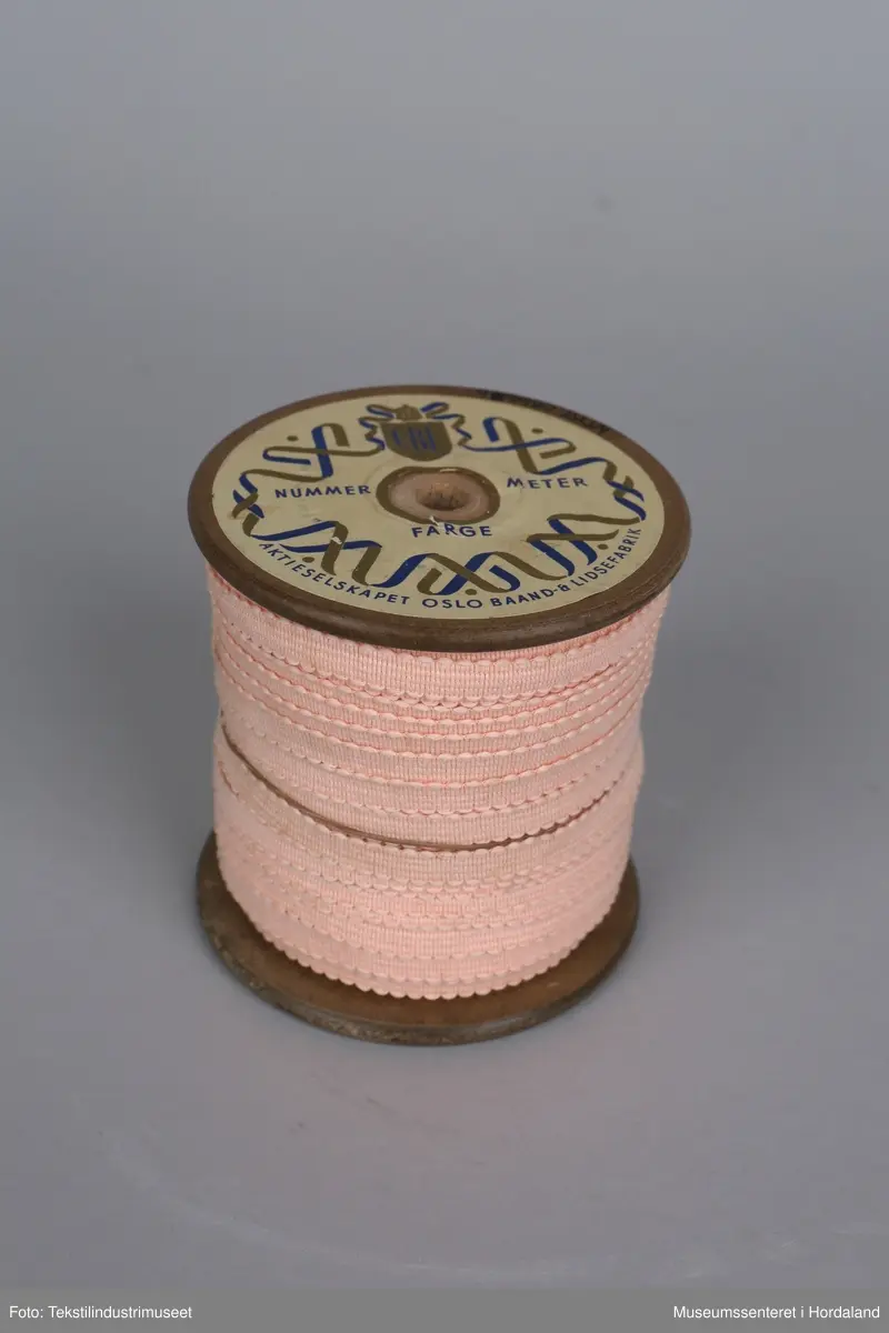 Spole med rosa pynteband (74 meter) produsert ved Oslo Baand- & Lidsefabrik.