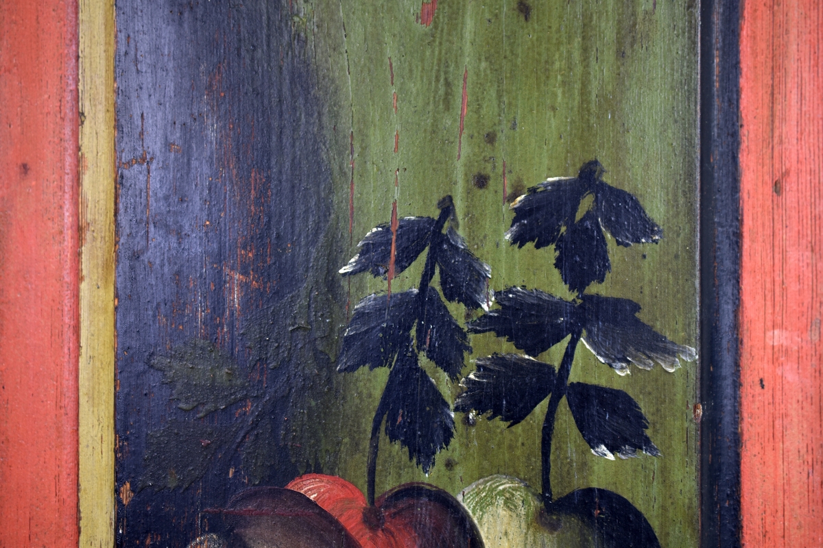 Rektangulär fyllning till skåpsdörr. Röd kant runt dörrfälten där en skål med tre äpplen är avbildade.