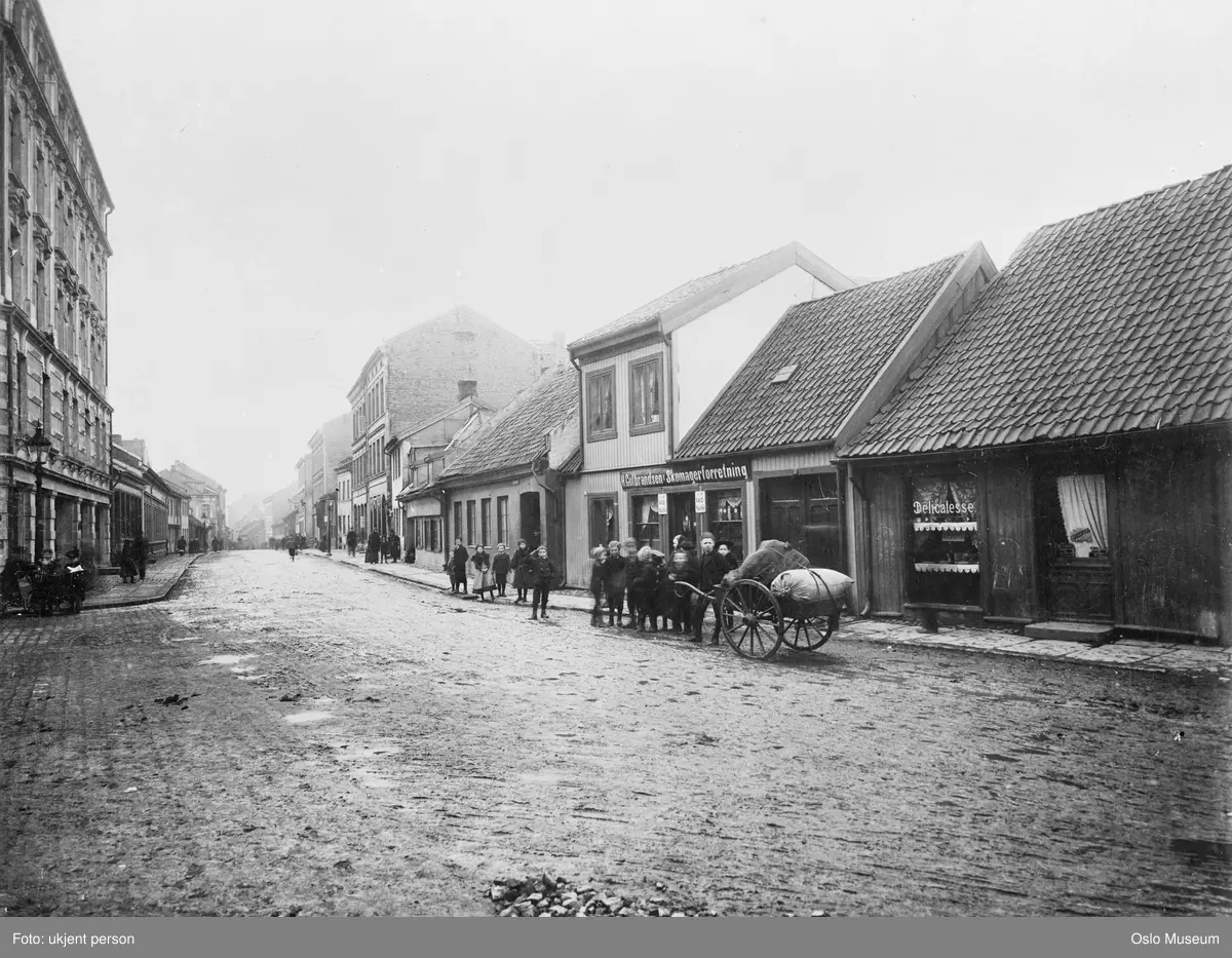 gateløp, trehusbebyggelse, mennesker, håndtralle, H. Gulbrandsen Skomagerforretning, Lakkegatens Melk- & Delikatesseforretning