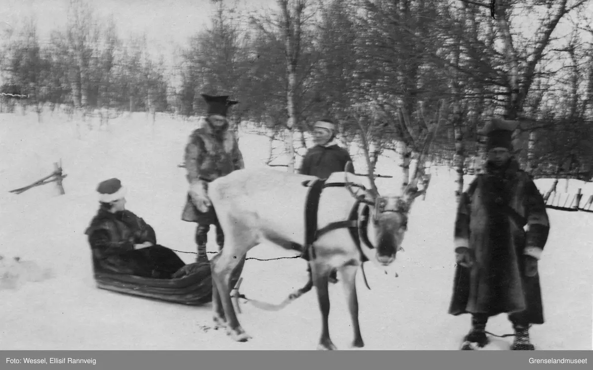 Ellisif Wessel sittende i pulk, tre samer, en kvinne og to menn, står ved siden av. Den ene mannen er sannsynligvis Ole Johnsen Must.