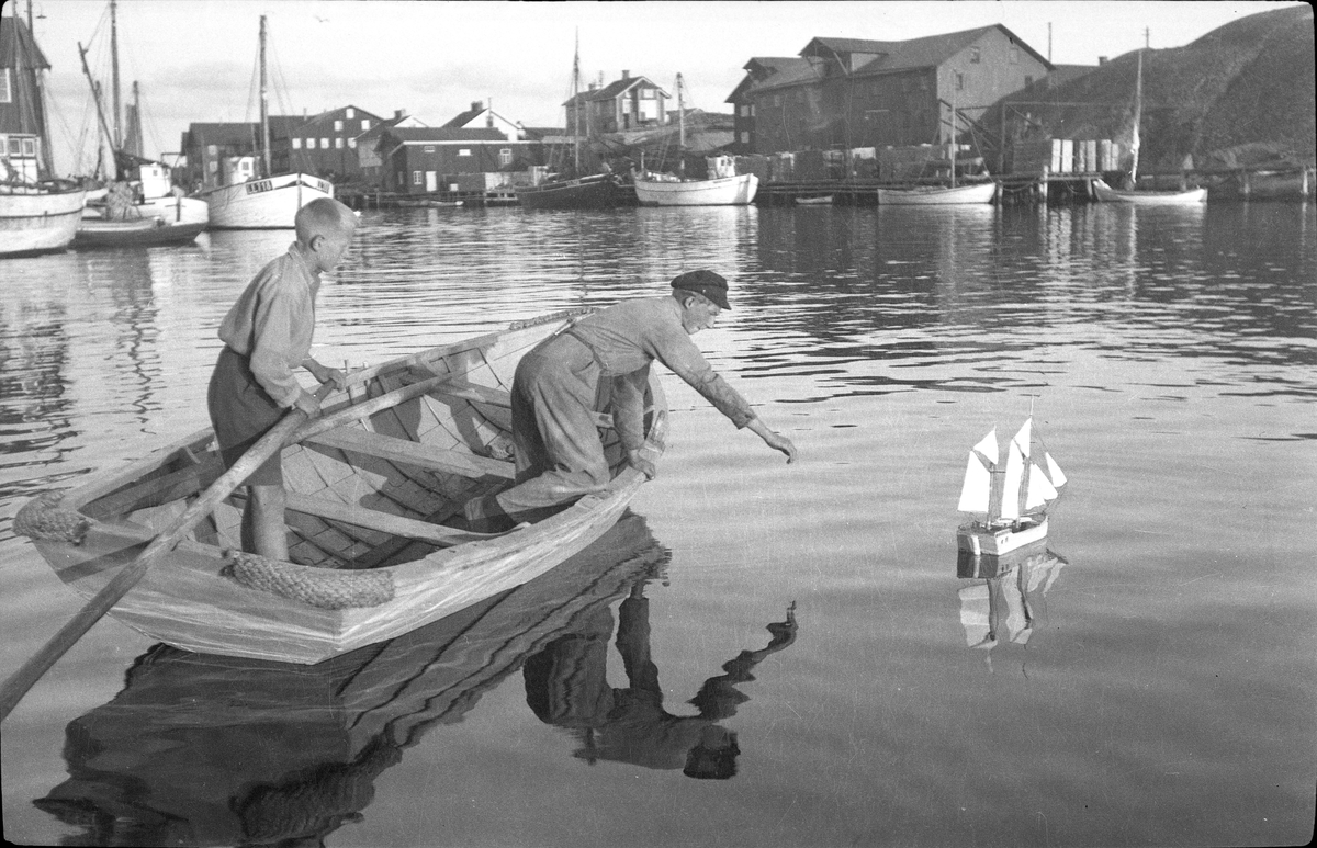 Fiskarpojkar lekande med båtmodell i Smögens hamn.
