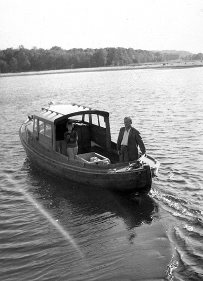 Enligt uppgift: ""Månvåg", arbetsbåt vid Bornö Hydrografiska station. Båten är byggd 1932-1933, överbyggnaden tillbyggd av Oscar Åkermo.
Ca 21-22 fot. Den äldre råoljemotorn utbytt mot Petter Diesel.
I båten syns Oscar Åkermo och dottern Solveig. Fotografiet är taget år 1959".