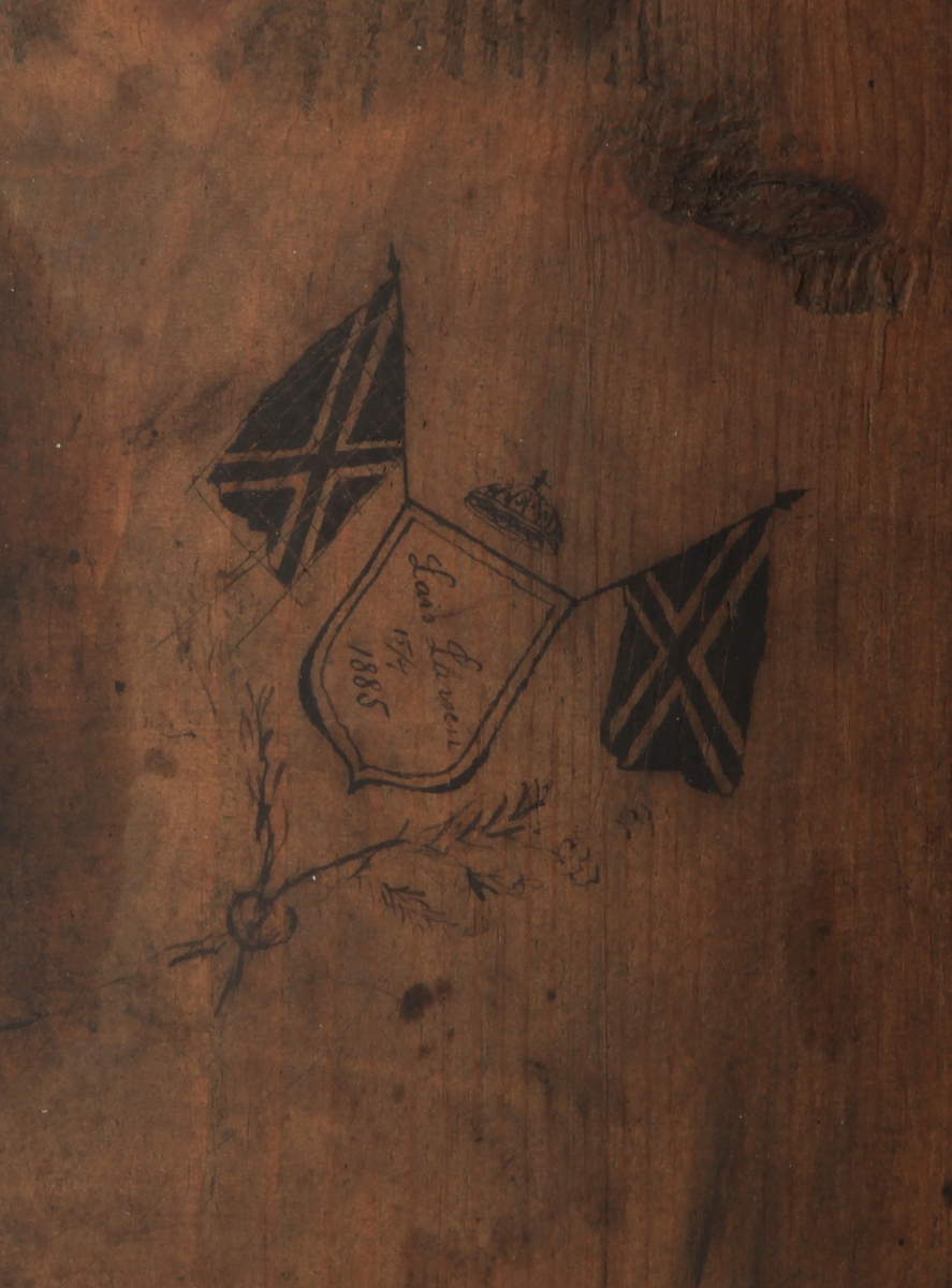 Rektangulært med skrånende skriveplate. To skuffer i front. Høye bein. Omtrent midt på beina er en hylleplate hvor det er hengslet en skapdør med en ring til håndtak. Skapdøren er hengslet i overkant og trekkes opp for å åpne.