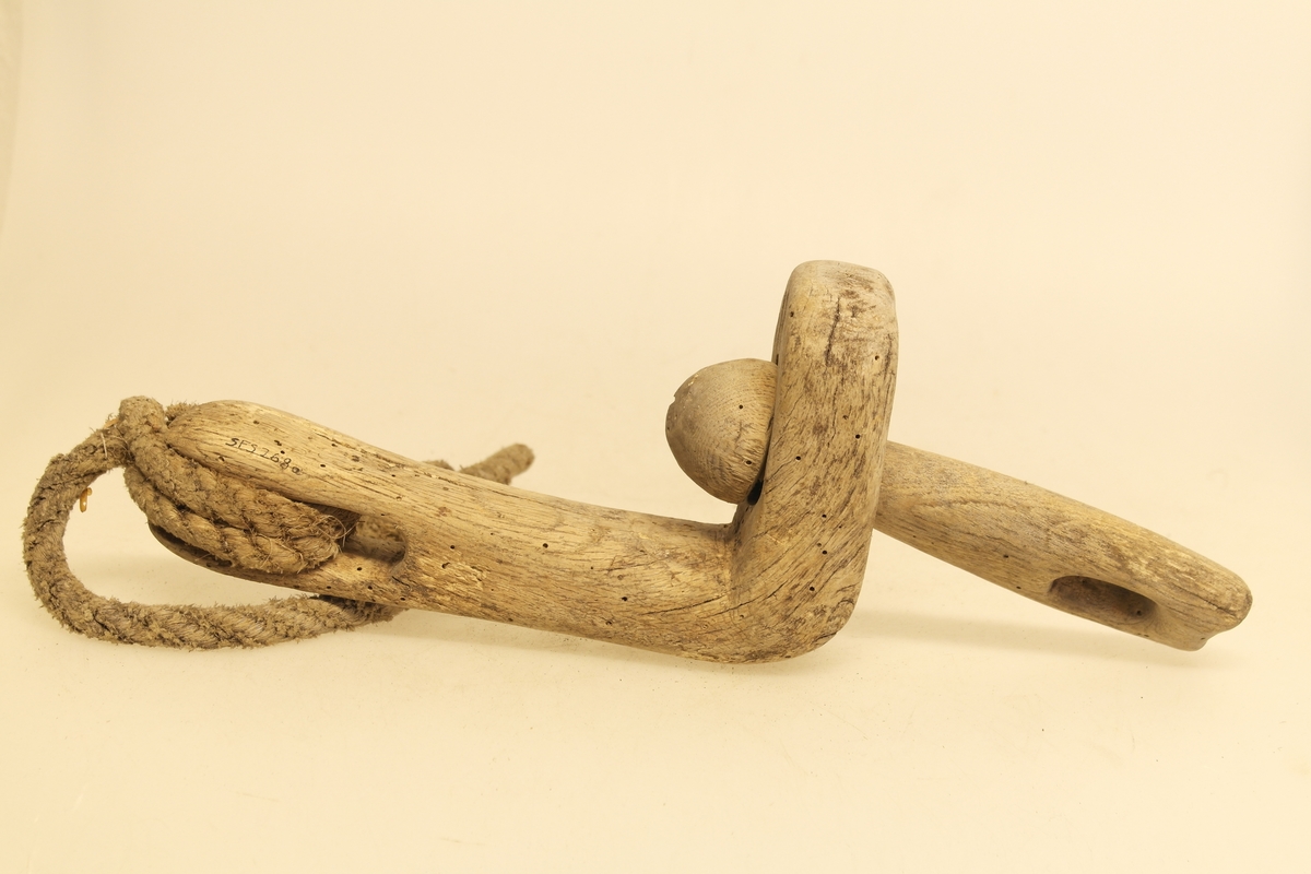 Veggband/Lekkjend i skåret eik. To ledd er skåret ut av samme trestykke, slik at begge kan svinge rundt. Utsparing i hver ende av leddene. Det er bundet et rep i det ene leddet.