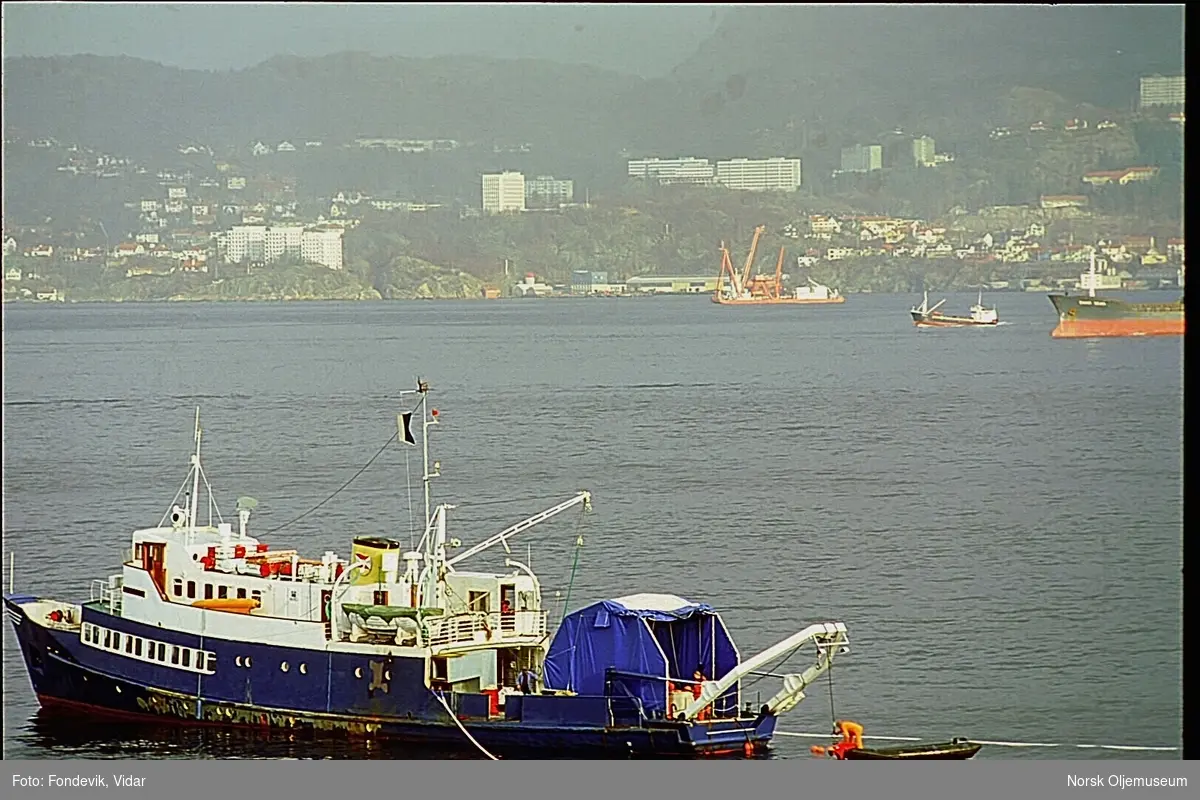 Dykkerskipet "Strilborg", senere omdøpt til "Deepsea Inspector" ligger i Byfjorden utenfor Bergen.  Dykkerfarkosten Check Mate er heist ned i vannet og befinner seg nedykket bak fartøyet.