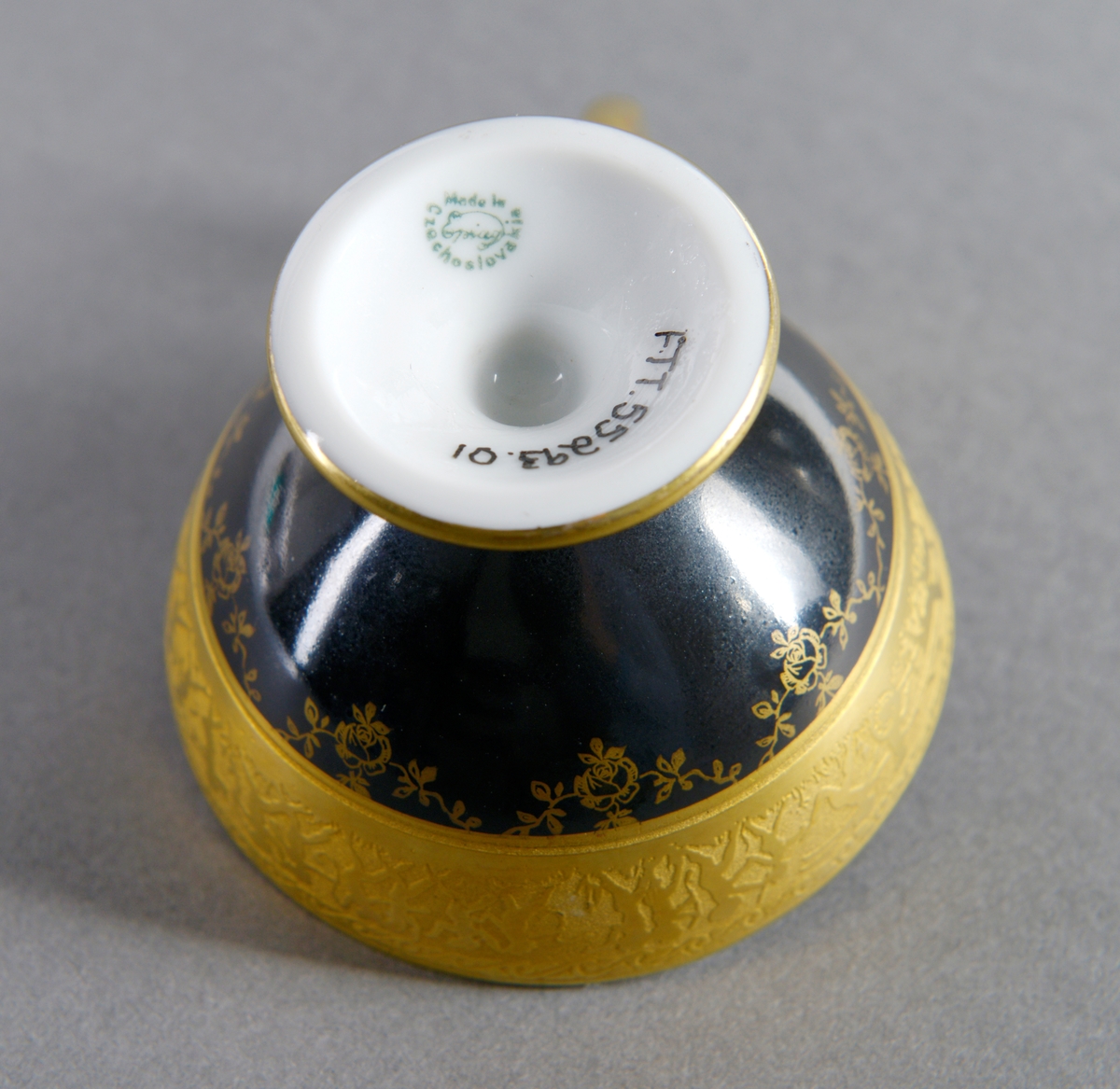 Gullkanten øverst på korpus er dekorert med en scene hvor mennesker danser, løper med dyr, rir, sykler og spiller på instrument. Under denne kanten er koppen dekorert med rose- og bladmønster i gullfarge over det kulørte.