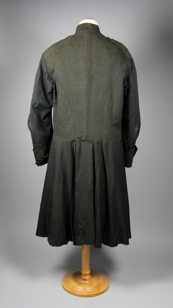 Rock av svart tuskaftsvävt yllekläde. Rocken har en 3,5 cm hög ståkrage. Ärmarna har två längsgående sömmar och 11 cm breda uppslag. Ryggstycket är sammanfogat av fyra våder. Vid axlarna är en trekantig kil infälld på var sida. Troligen en besparing. I höfthöjd har rocken en mittsöm som löper hela vägen runt. Skörten är skurna med stort omfång och rundade. I mitten bak är båda skörten förlängda med en remsa som överlappar på höger sida i ett sprund. Nederkanten har på flera ställen infälda stycken, troligen för att utnyttja tyget maximalt eller som lagningar. Rocken stängs fram med 9 par hyskor och hakar av grov mässingstråd.

Fodret är sytt av minst tre olika tyger. Överst ett grövre grårandigt linnetyg med två infällda innerfickor. Ärmarna är fodrade med oblekt linne och har vaddering av bomullsvadd. Nederst i båda ärmsluten finns rester av blåfärgade linneremsor. Kanske ett tidigare fodertyg eller ett mellanlägg. Rockens nedre foderdel är av ett tunt linne eller bomullstyg med tryckt mönster i brunt på ljusbrun botten. Möjligen är den övre delen av fodret yngre än den nedre. Slitaget på den övre är mindre än på de nedre. Hela rocken är handsydd, men det förekommer lagningar och bättringar med raksöm från symaskin. Det finns flera mindre och några större hål samt sömmar som släppt.