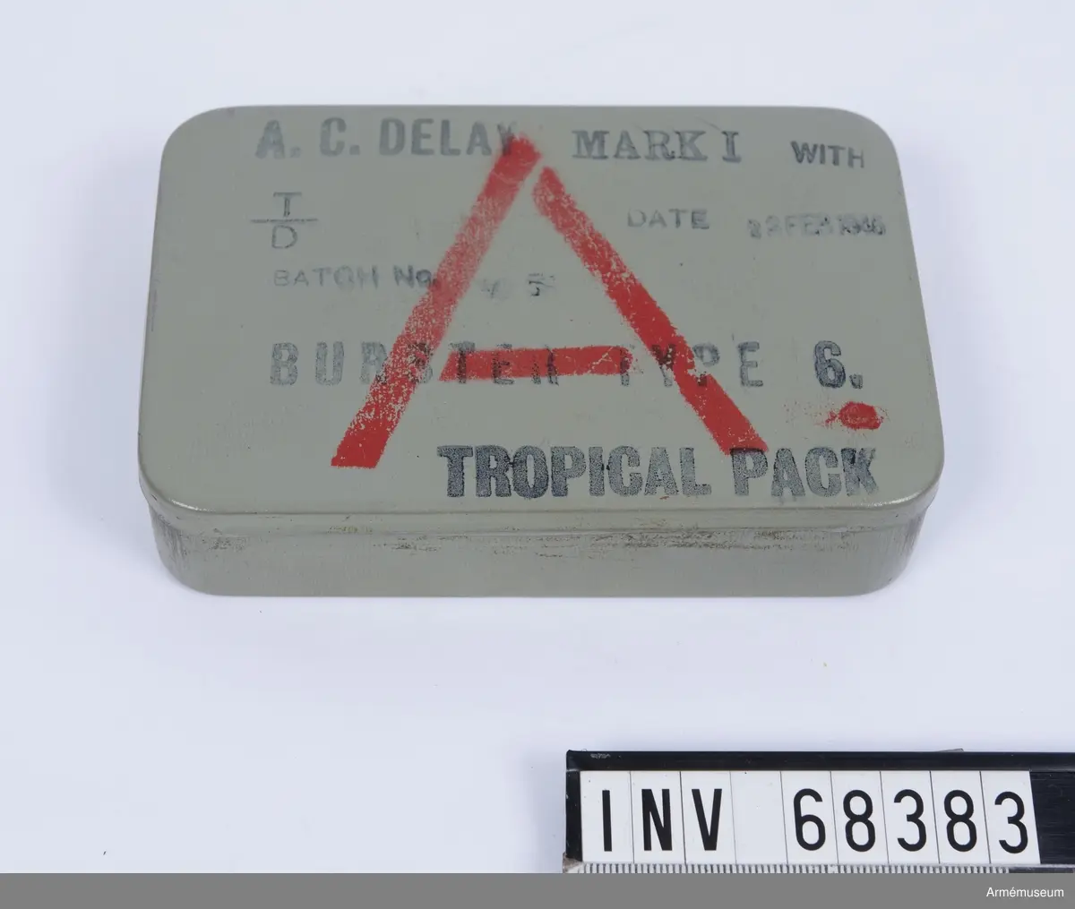 Grå plåtlåda med 6 ampuller innehållande acetonlösningar för olika tidsutlösningar.
Burster type 6.

A.C. Delay Mark I, TROPICAL PACK, Utlösare till fästmina:

With T/D Batch no (oläsligt), DATE 23 FEB 1945
BURSTER TYPE 6. TROPICAL PACK. A. 

Inklusive tändanordning och 6 st färgampuller med beskrivning. 
Acetone Celluloid
På instruktionen på insidan Type B
Vid 15 grader C fördröjs ampullernas utlösning med:
•	Röd 4 ½ time
•	Orange 7 ½ time
•	Gul 15 timmar
•	Grön 26 timmar
•	Blå 42 timmar
•	Violett 5 ½ dag
Notera att det kan ske en avvikelse på 15 % åt vardera hållet förutom Röd då avvikelsen kan vara 2 timmar åt båda hållen.