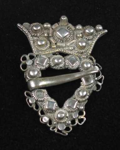 Krusesprette av sølv med løkker. Krona er loddet til hjertegrinda. På midten har den en tredobbel diamantkruse omgitt av små perler og perlekruser. Langs kanten er det pålagt tvinnetråd. Hjertegrinda er utvendig og innvendig kantet med tvinnetråd. På forsida er den dekket av perlekruser og diamantkruser. (En perle mangler.) Langs kanten er det trådløkker satt sammen tre og tre. (Deler mangler.)Tornen er festet på tvers av hjertegrinda. Krona ser ut til å være forgylt.