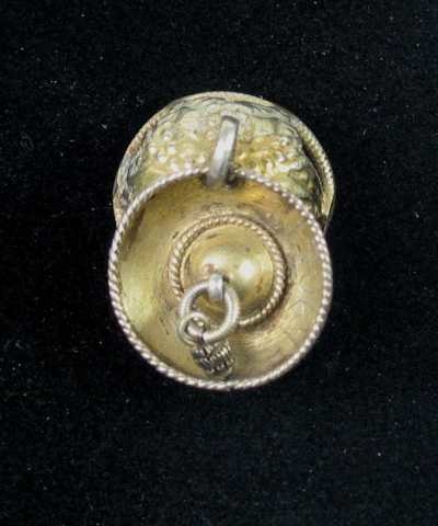 Drevet malje av forgylt sølv med skåleløv. Bunnen, som er tilklipt av sølvblikk og ender i små bladspisser, er mønstret med drevne eller dorete små punkter. Rundt kanten er det en ring av skruetråd. Tvers over ringen er det loddet en tynn sprosse. I en stor løkke midt på bolen henger det et forgylt skåleløv som igjen bærer en mindre løkke med ring og krusedobbe. I bunnen og langs kanten er det lagt en tvinnetrådsring. Ingen synlige stempel.