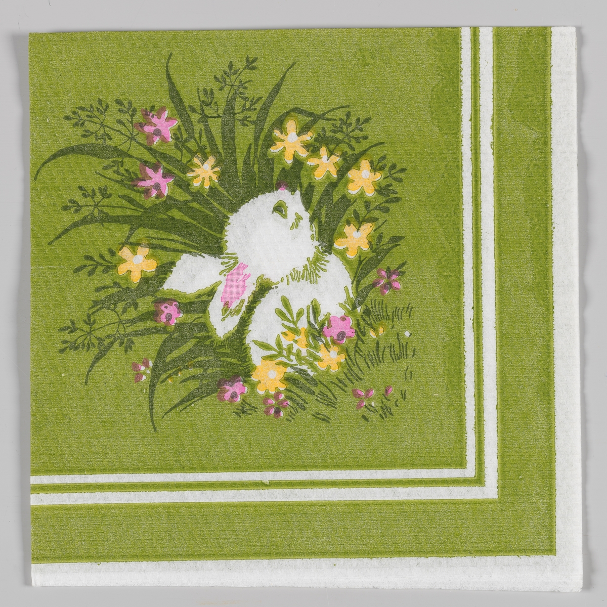 En liten harepus som gjemmer seg i høyt gress med gule og rosa blomster. Hvite og grønne kantstriper.
