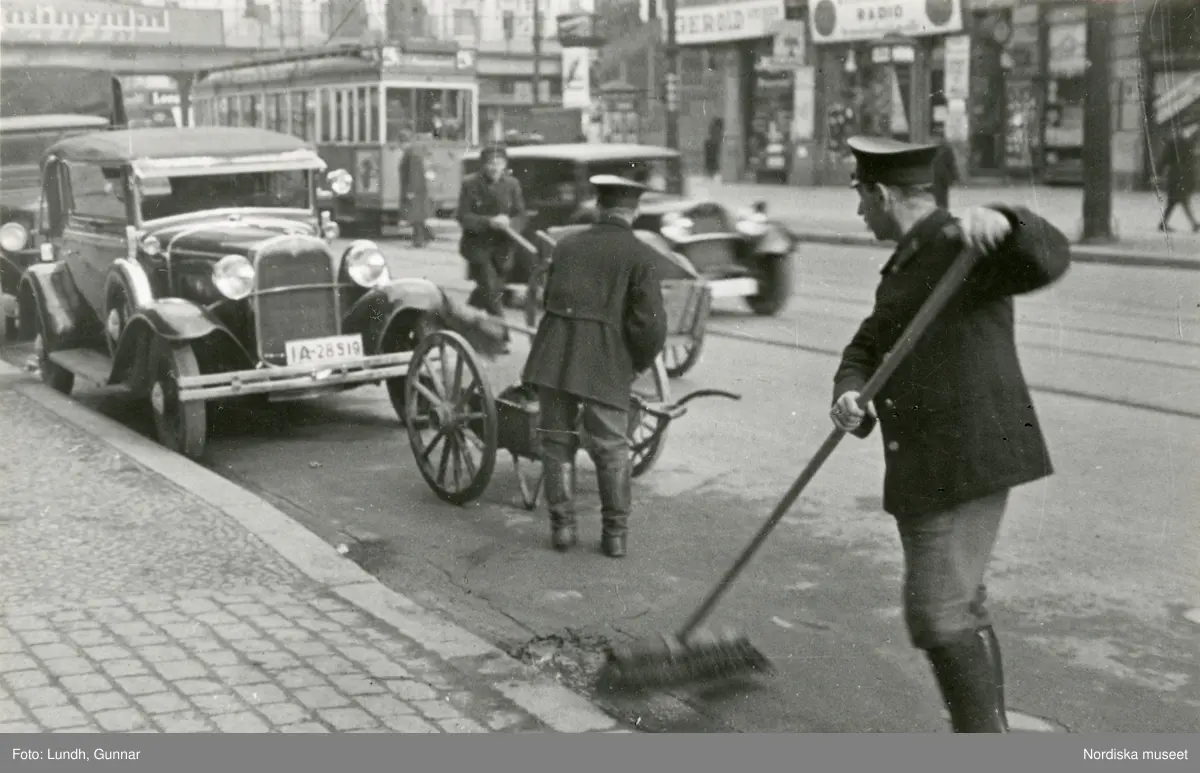 Berlin. En gatsopare i arbete, i bakgrunden trafik