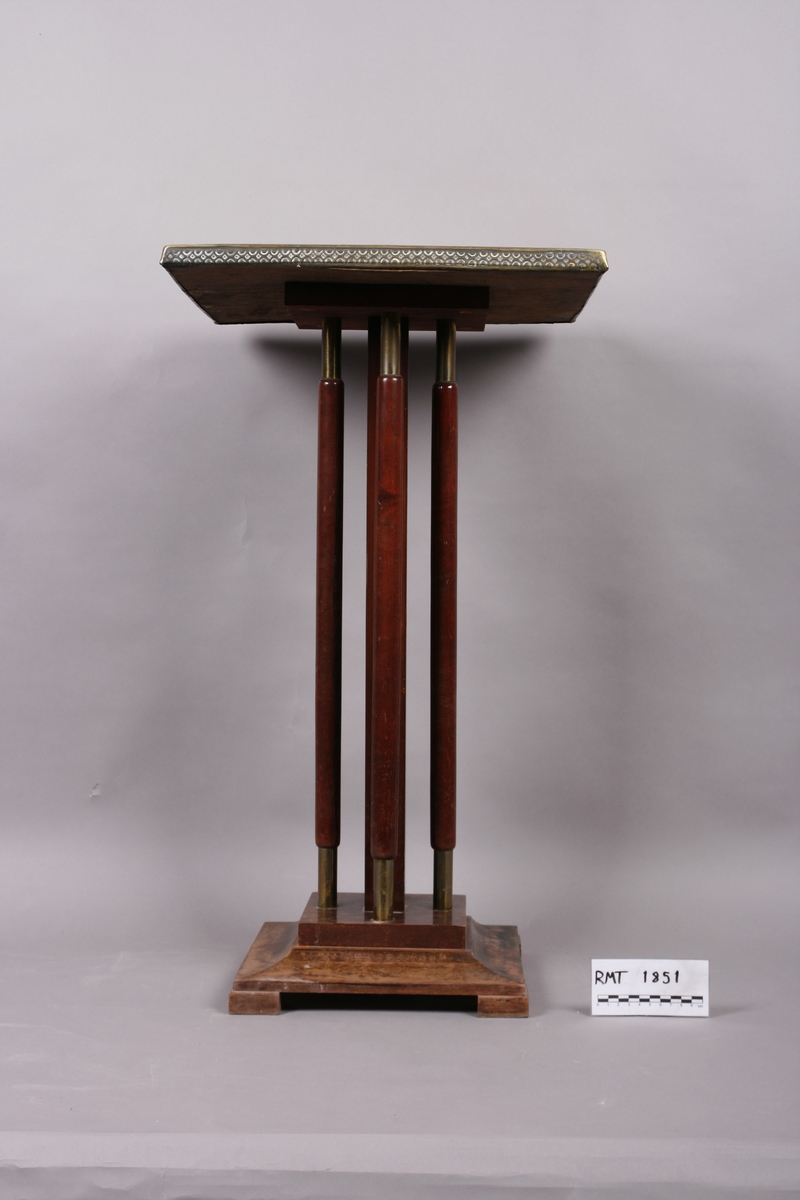 Firkantet med fire søyleben. Bordplate i messing med preget dekor.