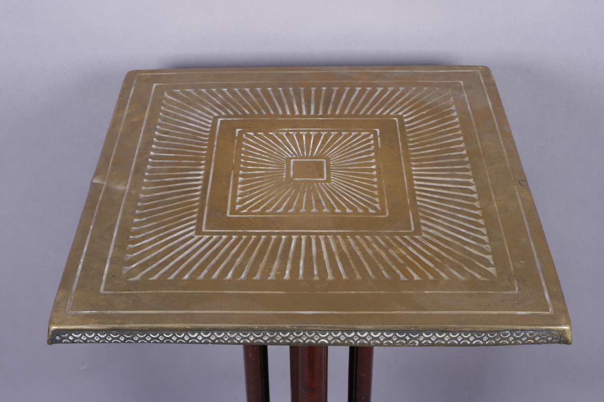 Firkantet med fire søyleben. Bordplate i messing med preget dekor.