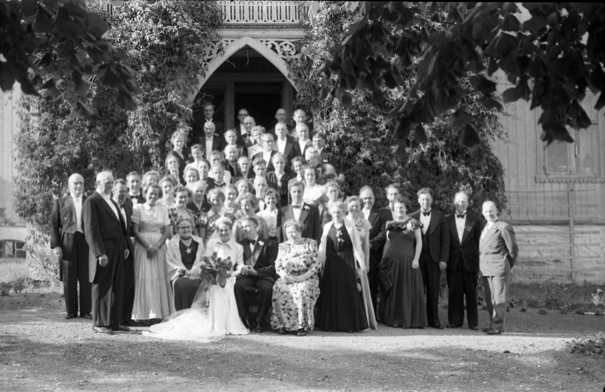 Bryllupsfest på Hoff Gjestgiveri 12.juli 1952. Brudeparet, Else Rustad og Edvard Narum, sammen med gjester fotografert foran gjestgiveriets hovedinngang. Til høyre for brudgommen sitter hans mor, Signe Narum. Til venstre for bruden hennes mor Betsy Marie Rustad, og til venstre for henne Kari "Mosse" Larsen (f.Rustad). Bak henne igjen står hennes mann Ernst Larsen (m/tversoversløyfe). Lengst til venstre står muligens Hans Rognerud. Fire bilder.
