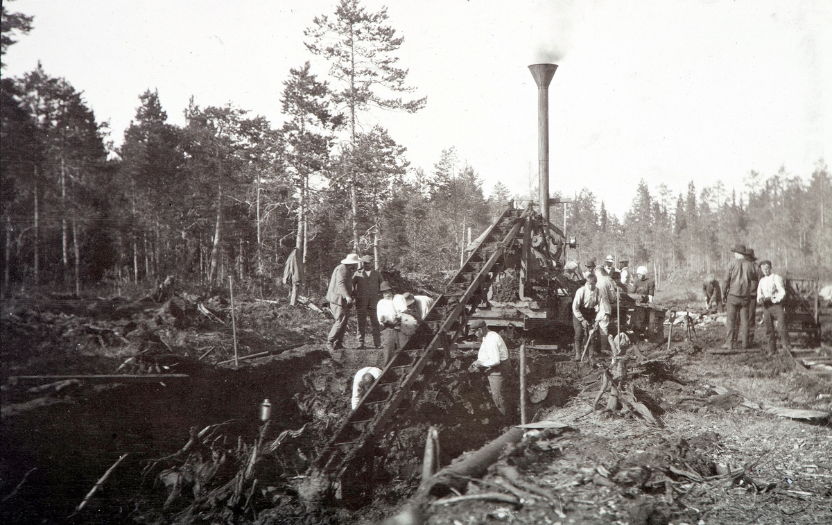 Arbeidere ved torvfabrikk, sannsynligvis Løten. Torvmyr, lokomobil, damp.