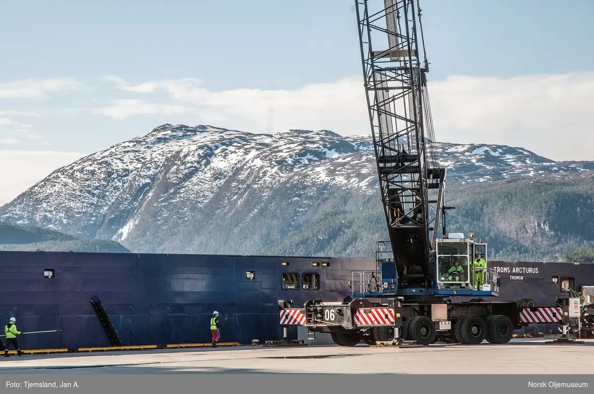 Forsyningsfartøyet Troms Arcturus ligger ved kai på Vestbase i Kristiansund, og en stor mobilkrane sørger for lossing og lasting.