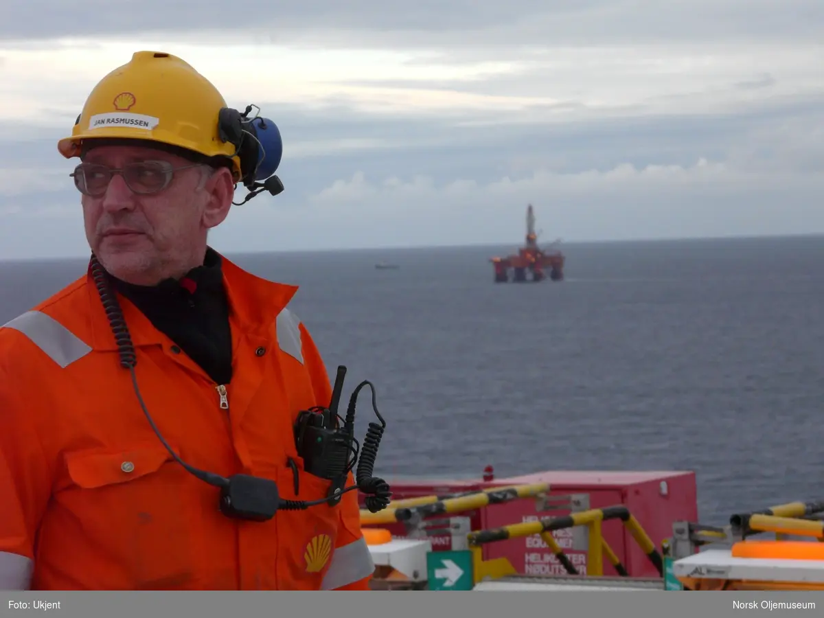 Jan Rasmussen på helidekk. I bakgrunnen ligger boreriggen Transocean Arctic.