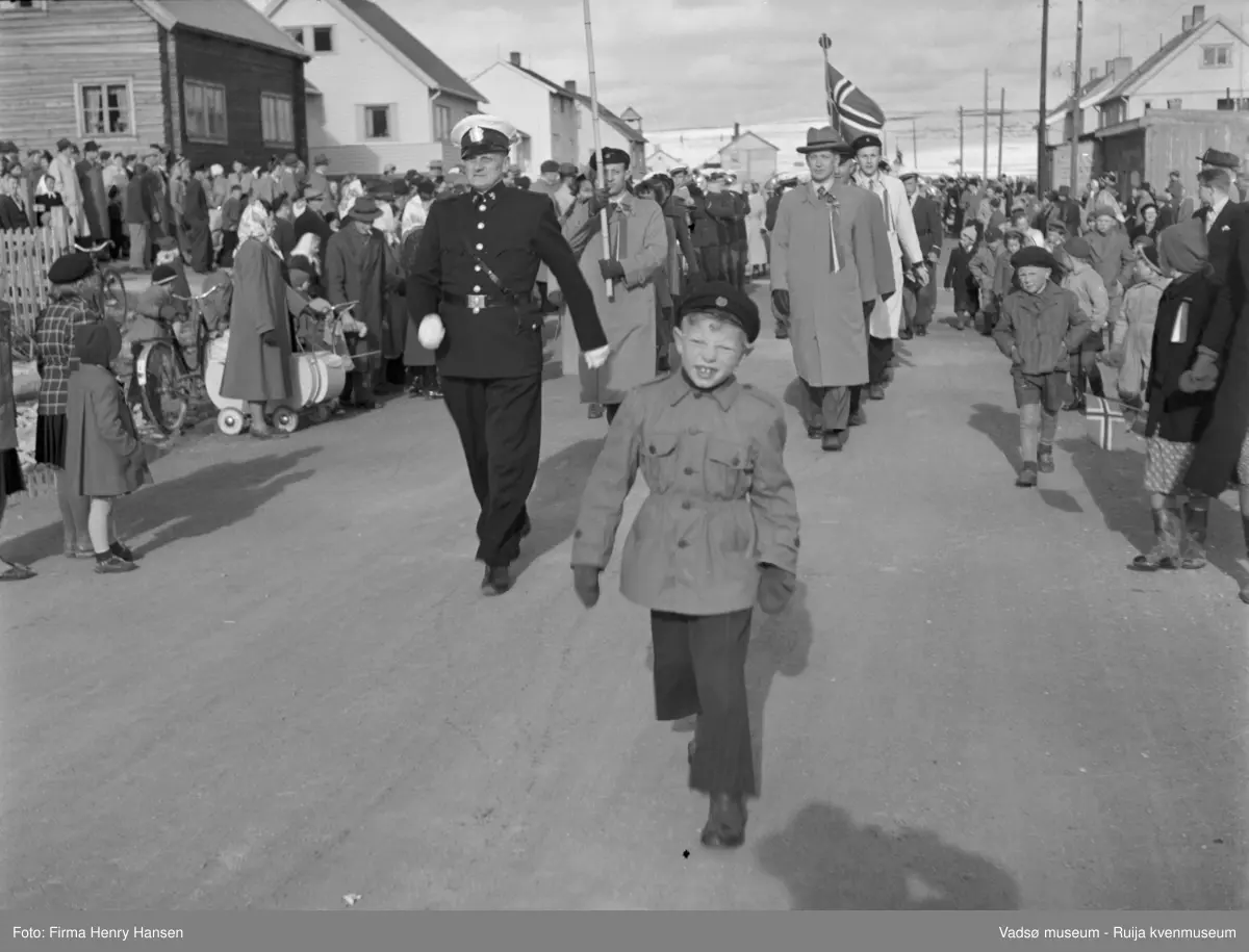 Vadsø 17 mai 1952. 17.mai-toget med politimester Wickstrøm først i toget foran 17.mai-komiteen. Bildet er tatt i Oscarsgate. Gutten foran i toget er Hans Petter Holko. Det kan være Per Bjørgan som går til venstre i toget som nr to i lys frakk og studentlue.
