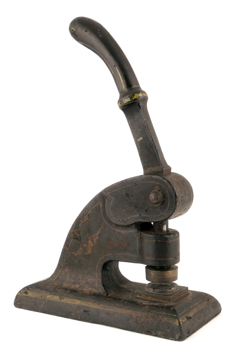 Stempelpresse av metall, sortmalt med gulfarget utsmykking. Fra Sarpsborg. Stempel: "Sarpsborg Toldoppsyn"