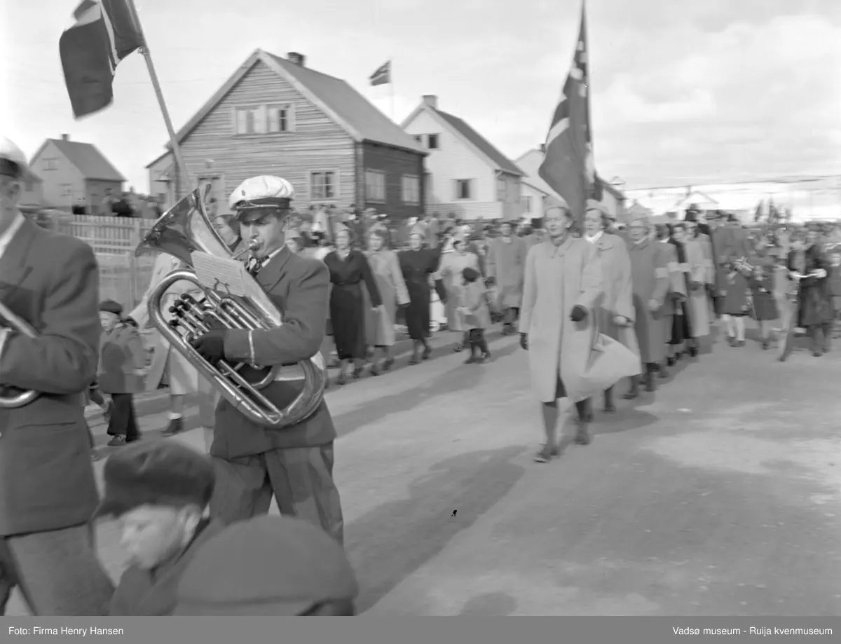 Vadsø 17 mai 1952. 17.mai-toget går gjennom Oscarsgate fra øst mot vest. Ser åssiden Melkevarden i bakgrunnen. Musikant med hvit korpslue.