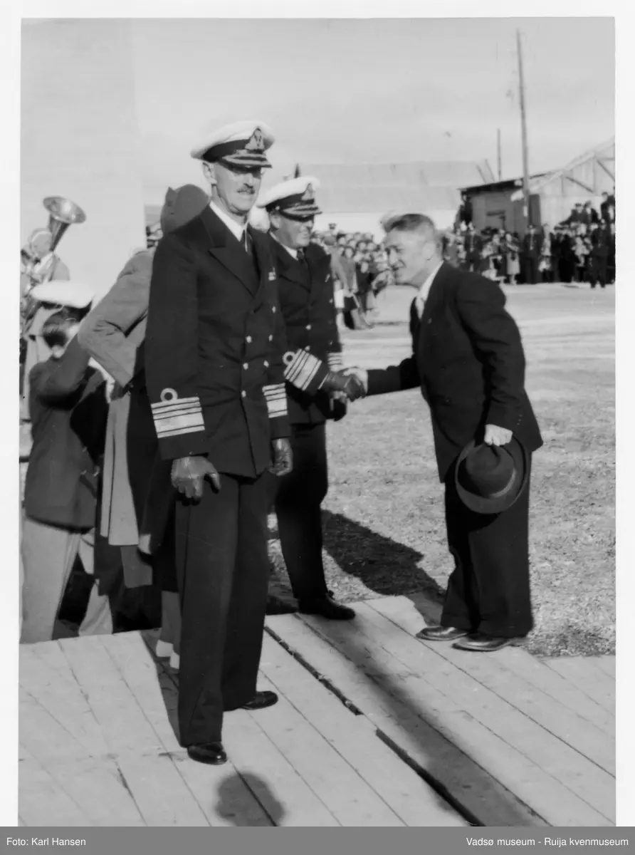 Vadsø. Kongebesøk i Vadsø 1950. Kong Haakon 7. og kronpris Olav blir tatt imot av fylkesmann Peder Holt. Kong Haakon og kronprinsfamilien besøkte Vadsø 25.-26.7.1950 i forbindelse med en større rundreise i Nord-Norge sommeren 1950. Under besøket sto "biltur gjennom byen" og "besøk på sykehuset" på programmet. Kilde: Det kongelige hoff, arkivet