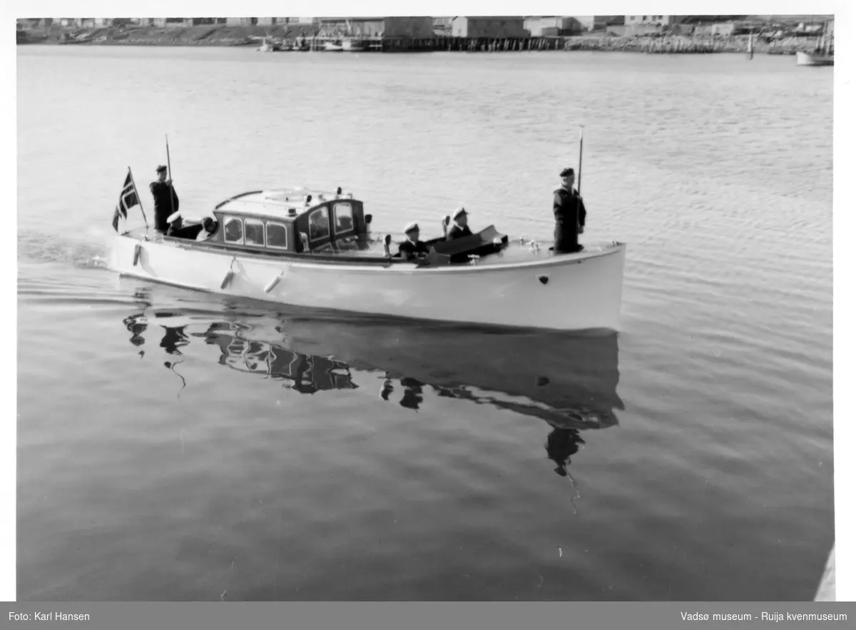 Vadsø. Kongebesøk i Vadsø 1950. Sjaluppen fra Kongeskipet Norge på vei til land. Kong Haakon og kronprinsfamilien besøkte Vadsø 25.-26.7.1950 i forbindelse med en større rundreise i Nord-Norge sommeren 1950. Under besøket sto "biltur gjennom byen" og "besøk på sykehuset" på programmet. Kilde: Det kongelige hoff, arkivet