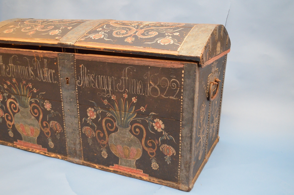 Rosemåla kiste med blomar, rankar, urner, prikkar og skrift. Påført skrift seier: Dortte Amunds Datter Mosagger Anno 1822.