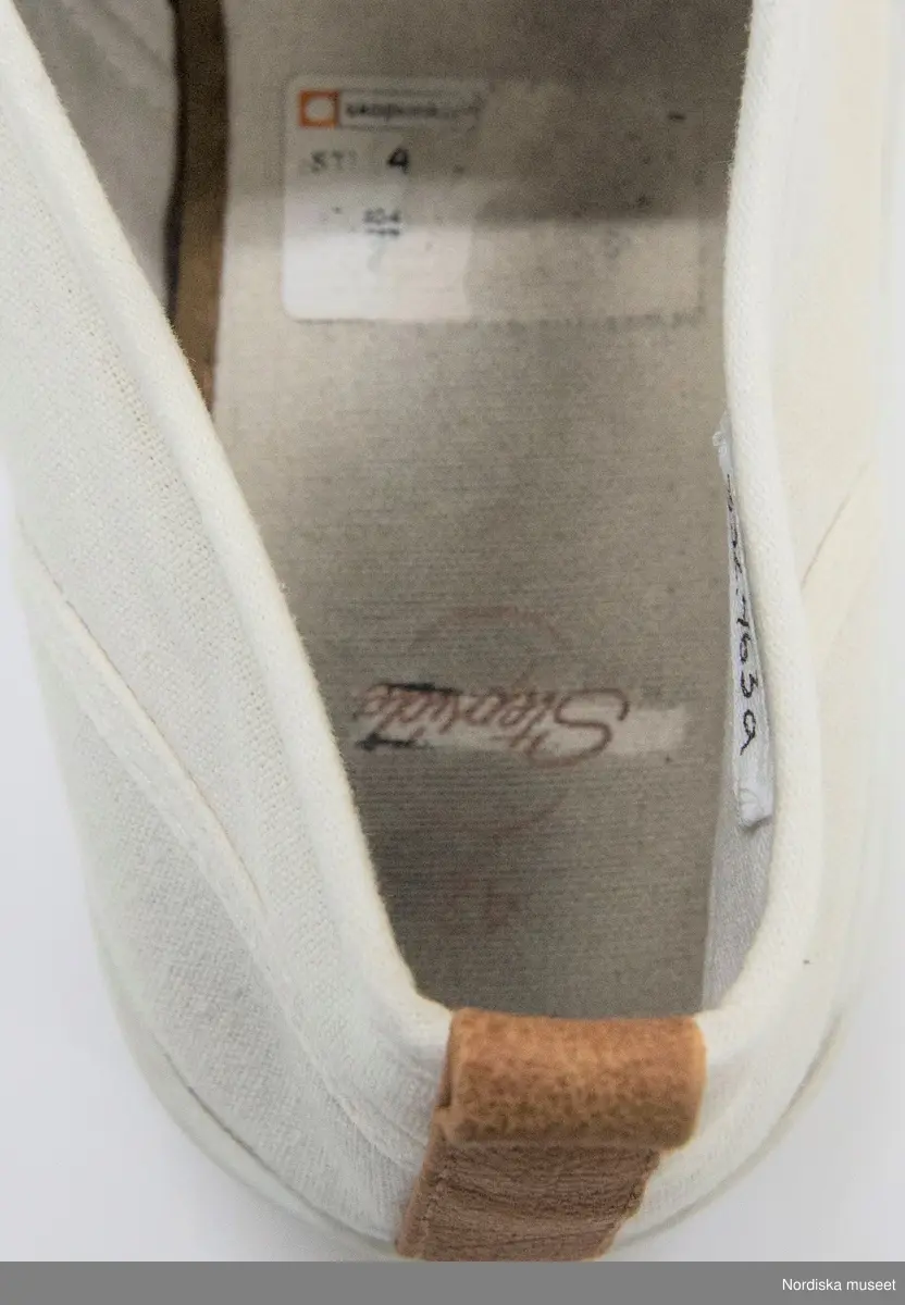 Ett par skor, vita. Sula av mjukt konstmaterial, överdel av textil (troligen blandning av bomull/syntet). Ovantill nätliknande mjukt tyg. På bakkappan brun ögla i läder. Resår vid kanten av ovandelen. Fodrad med vit textil. Innersula av vit textil med brun skoning. 
Etikett under ovandelen "42 81-305036 GOFO" och på innersulan "42 / Stepside". Under sulan storleksangivelse "42".  På innersulan på den högra skon rester kvar efter prislapp med text "Skopunkten...".
/Leif Wallin 2017-07-13