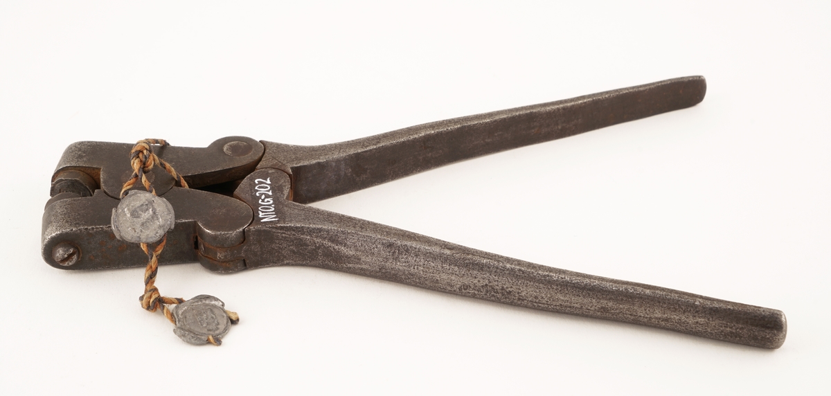 Plomberingstang av jern med tråd og to blyplomber festet til.