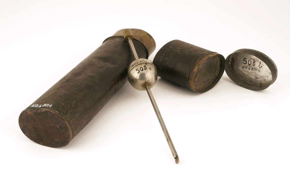 Alkoholmeter  av antatt sølv påmontert lodd .Etui med lokk. Lokket inneholder et ekstra rom for oppbevaring av  vekter til alkoholmeteret. Etuiet inneholder to rom for plassering av to alkoholmetere. Det mangler ett alkoholmeter.