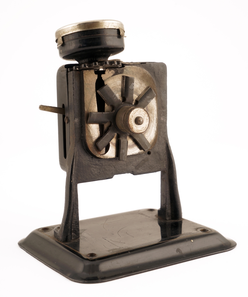 Blyantspisseapparat av  sortlakkert metall med dreiet håndtak i tre.