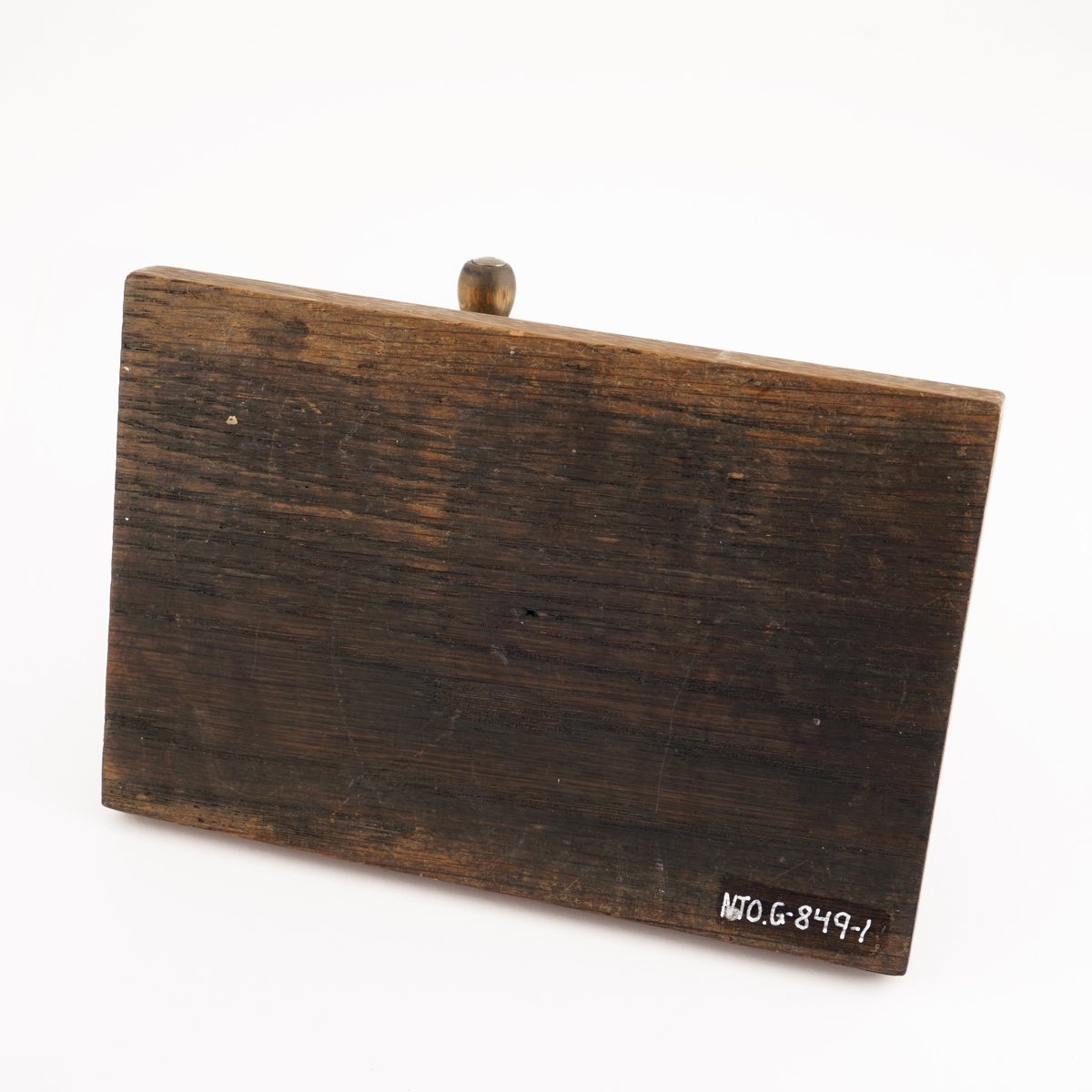 Blyantspisseapparat av  sortlakkert metall montert på treplate. Dreiet håndtak i tre.