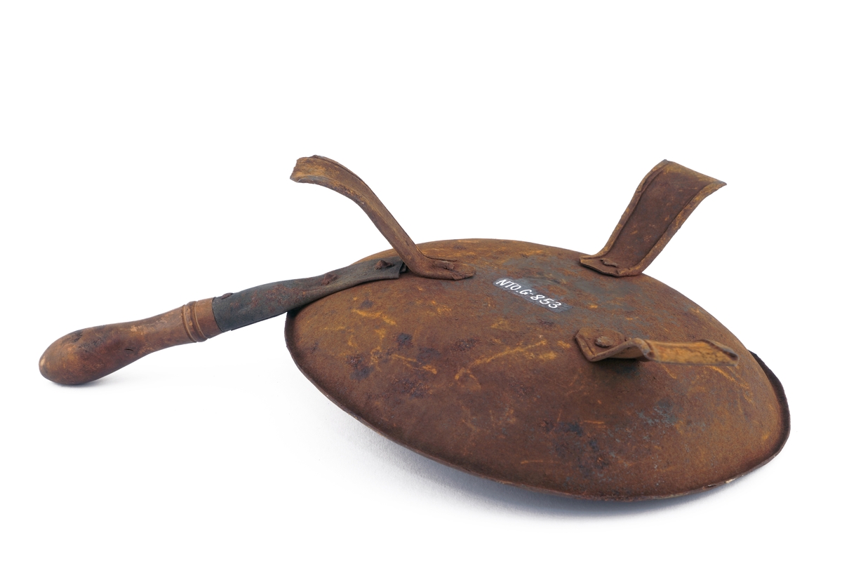 Panne av metall med trehåndtak på trebenet fot av bøyet blikk